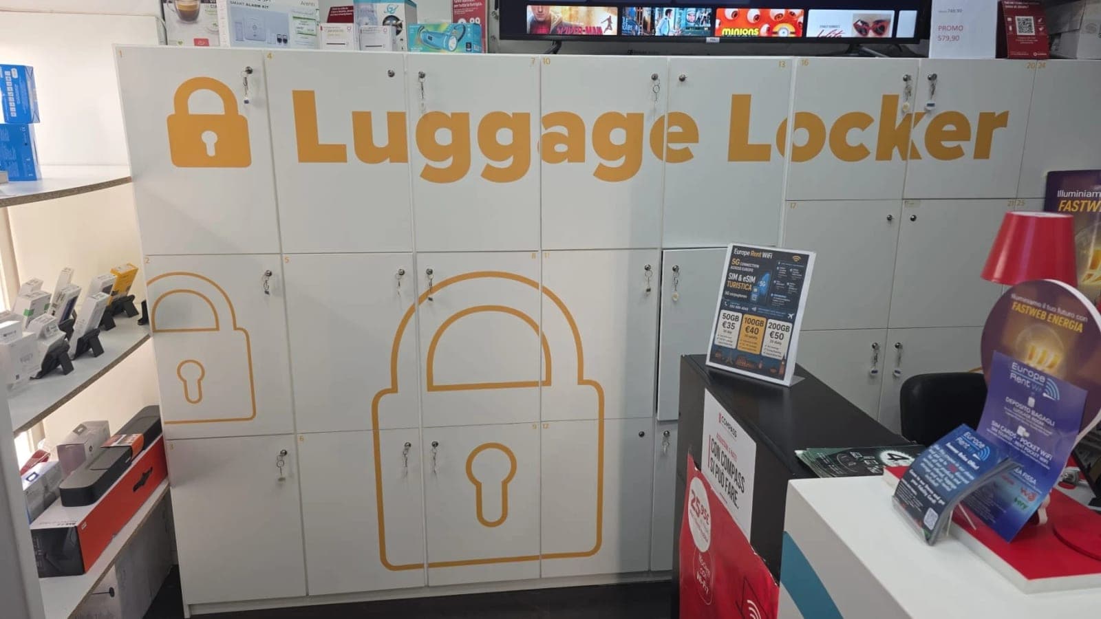 Numbered white lockers with keys at the Largo Alinari shop, under an orange "Luggage Locker" sign