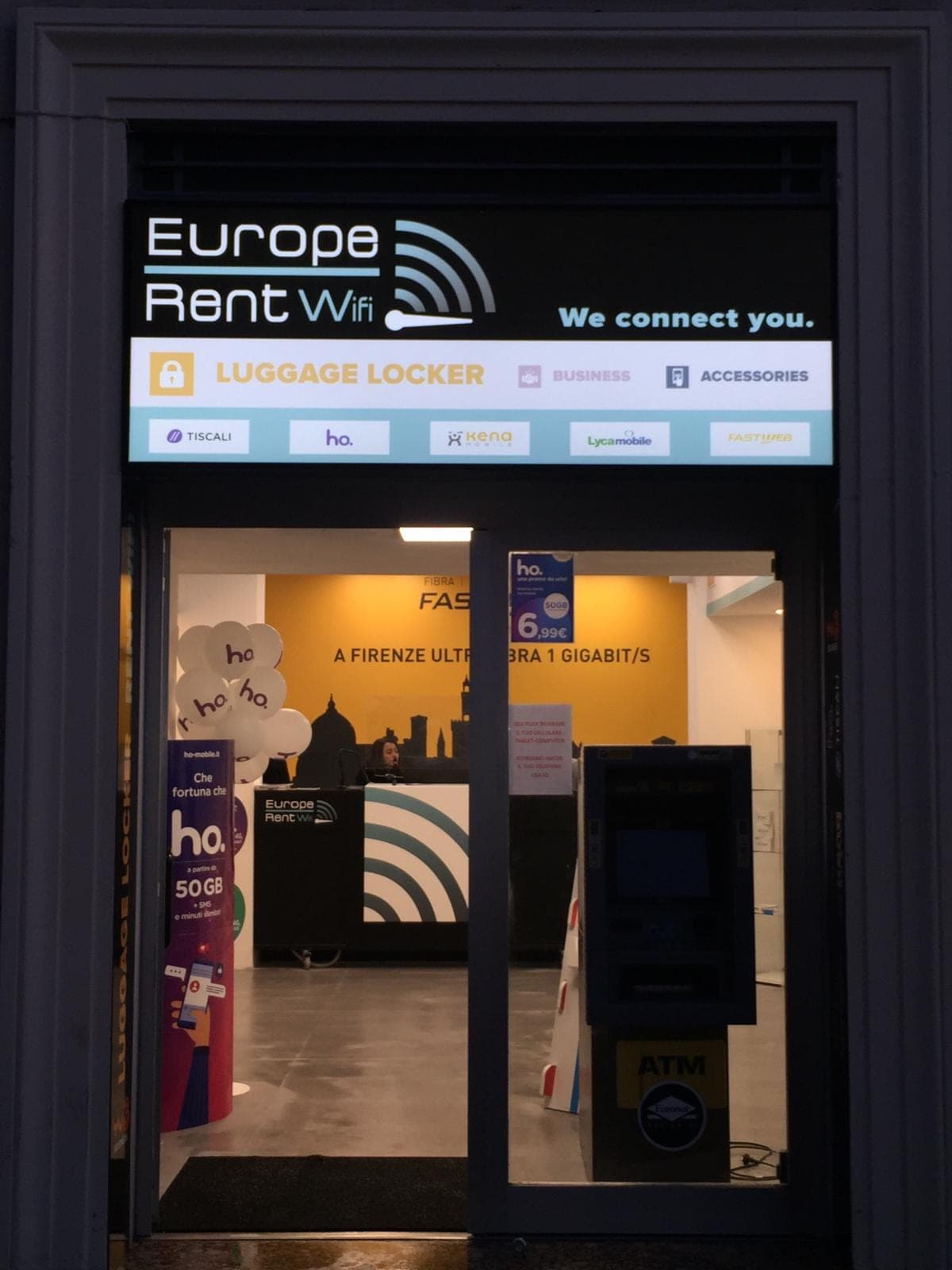 The Europe Rent WiFi sign and entrance at Largo Fratelli Alinari 27, Florence, lit up in the evening